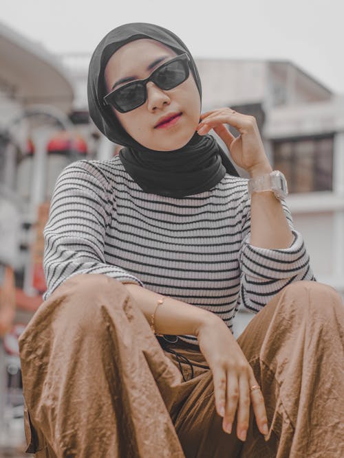 Young Woman in a Trendy Outfit and Sunglasses on a Sidewalk in City 