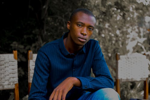 Young Man in a Blue Shirt Sitting on a Chair 