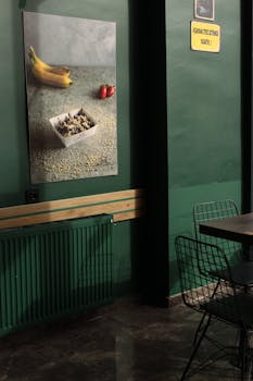 A modern interior with a green wall, stylish furniture, and an art poster featuring bananas and a bowl.