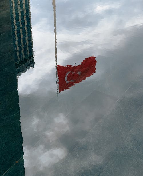 Blurry Reflection of the Turkish Flag and Cloudy Sky in the Water