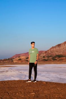 A man stands confidently in a desert landscape under a clear blue sky.