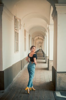 Fashion model posing elegantly in a stylish urban corridor, showcasing modern elegance.