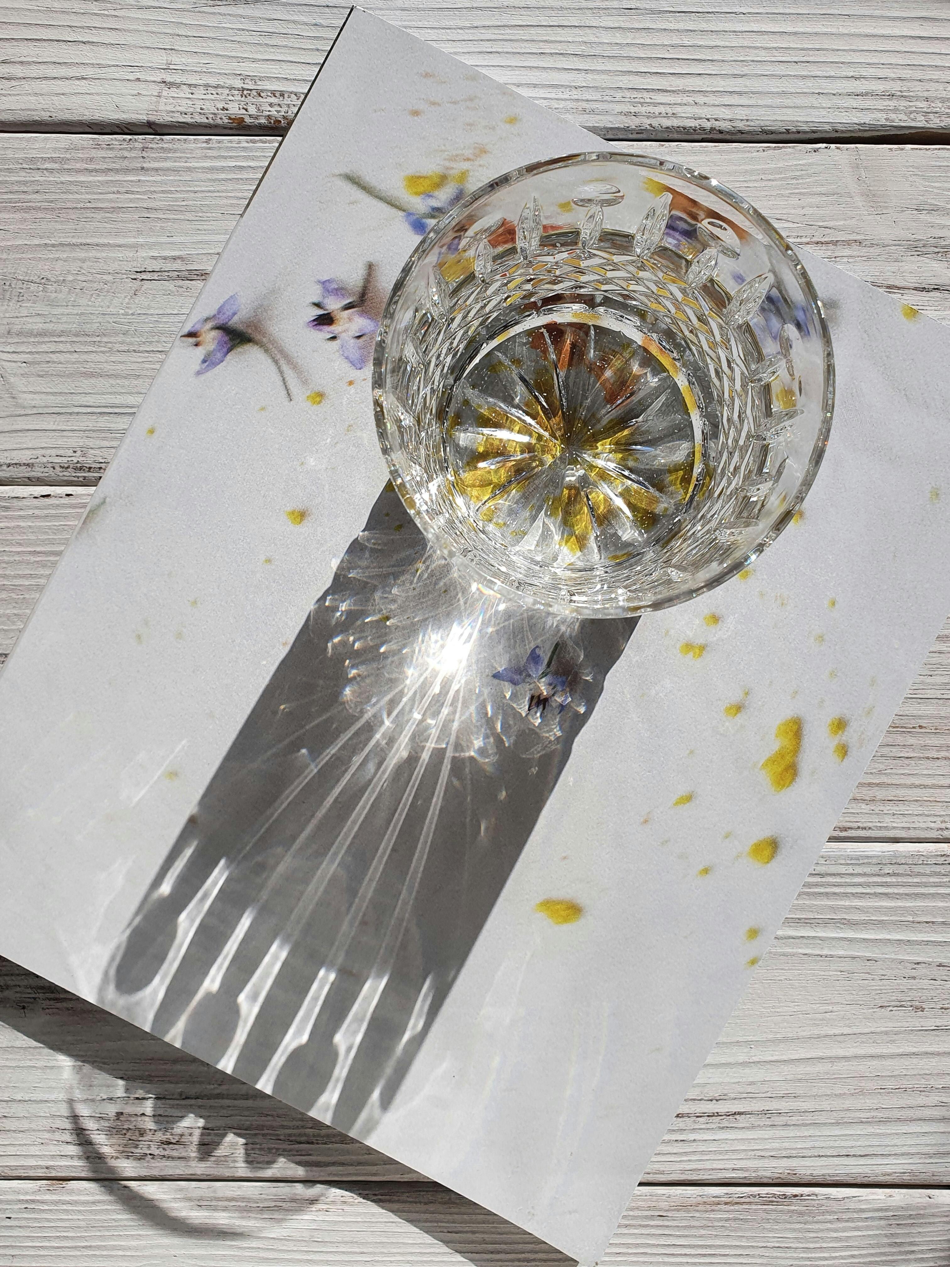 Crystal glass casting intricate shadows on floral backdrop, capturing elegance.