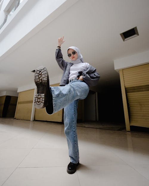 Woman in Sunglasses and Hijab Posing with Leg Raised