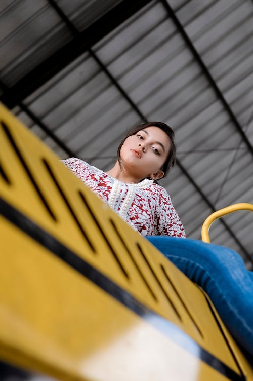 Pretty Woman in Sweater and Jeans Sitting on Yellow Surface