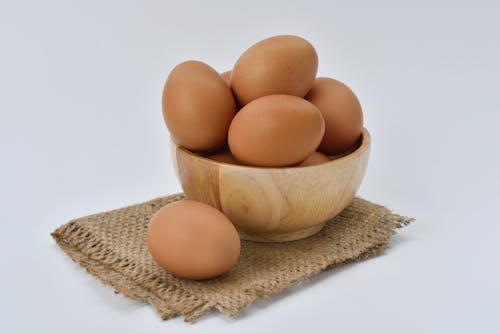 베이지 니트 직물에 갈색 나무 그릇에 갈색 계란