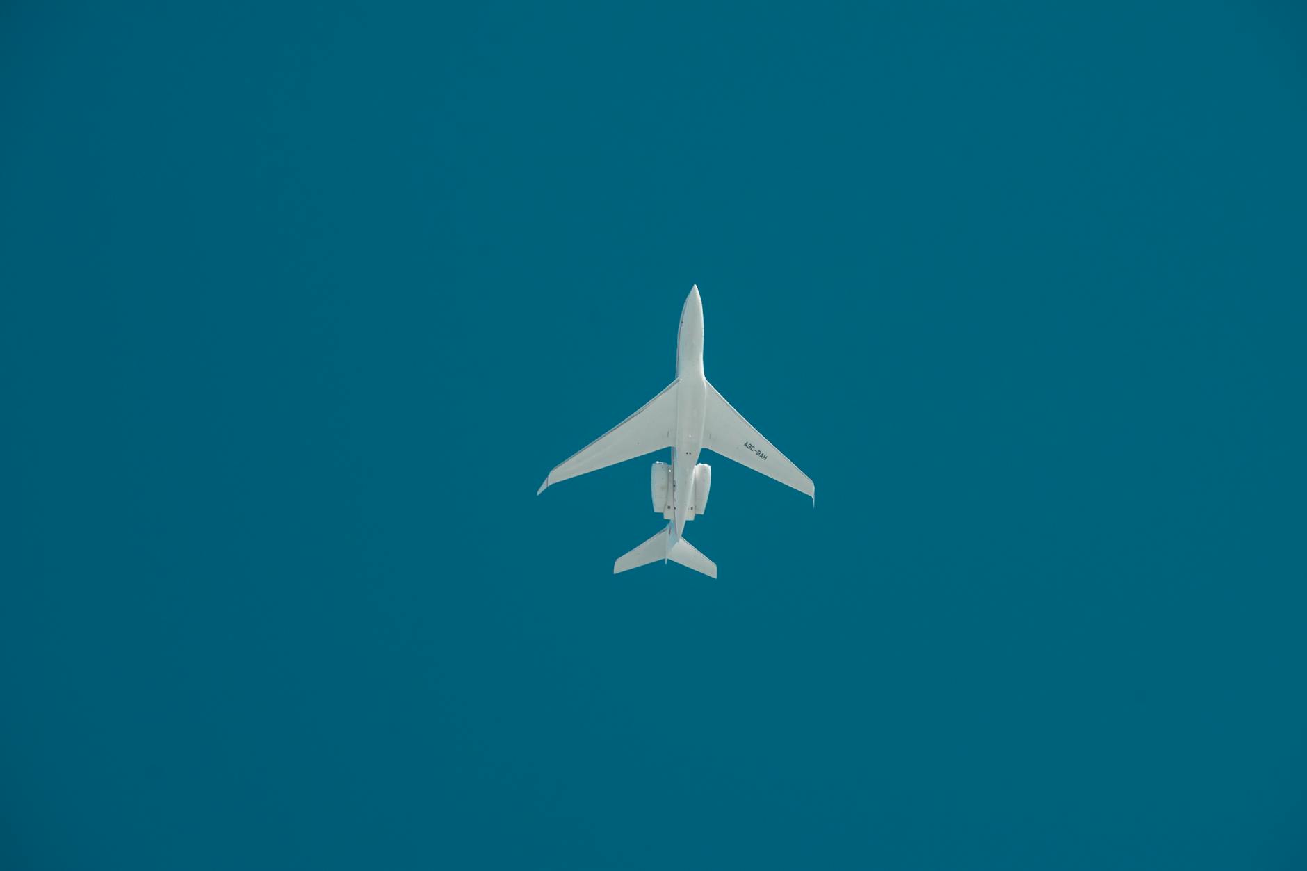 A commercial jet captured mid-flight against a deep blue sky in Dubai.