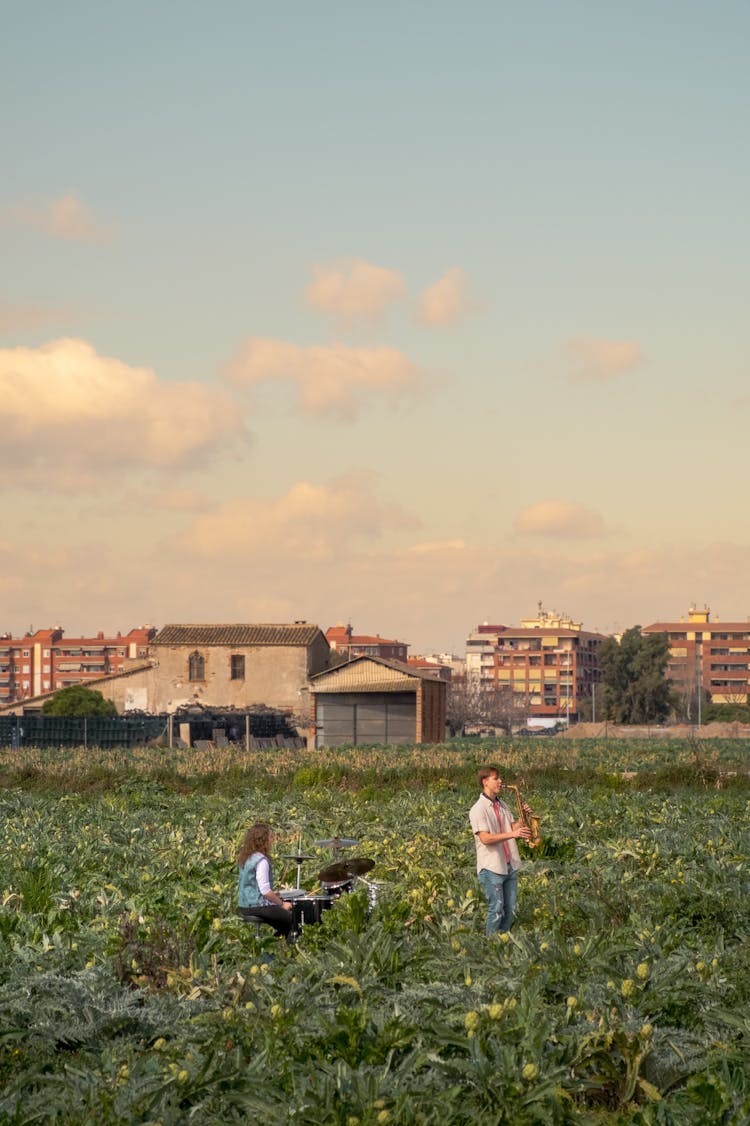 People Playing Music On Meadow Near Town