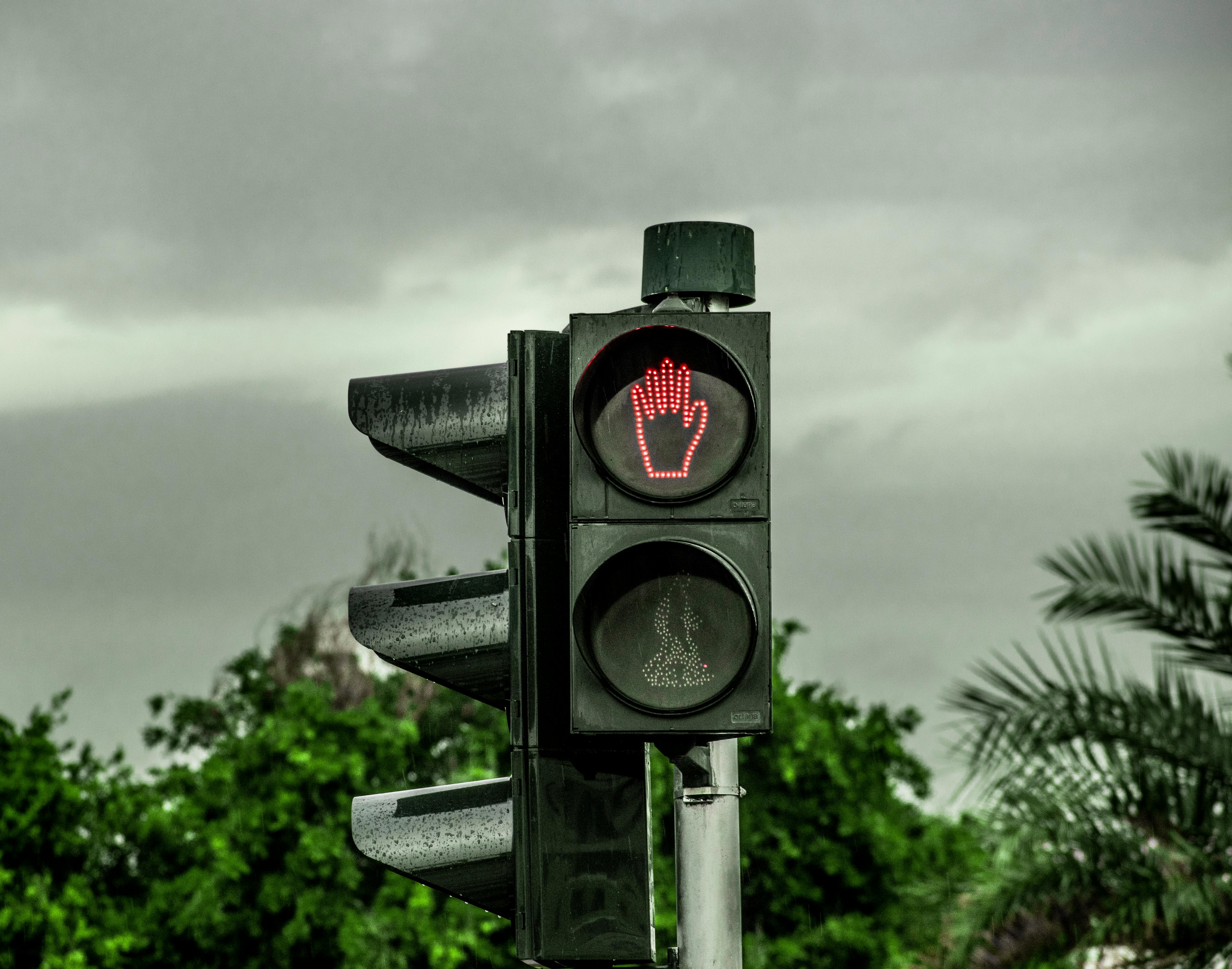 A pedestrian signal in Dubai displays a red light with an overcast backdrop.
