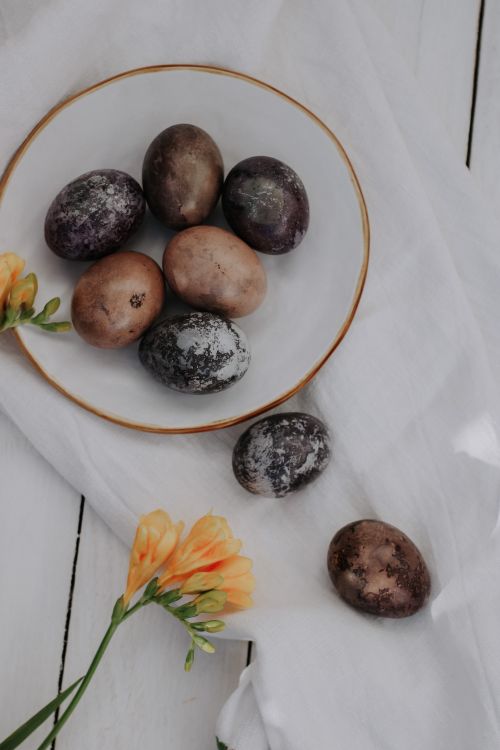 Free Artistic arrangement of decorated eggs with orange flowers on a rustic white table. Stock Photo
