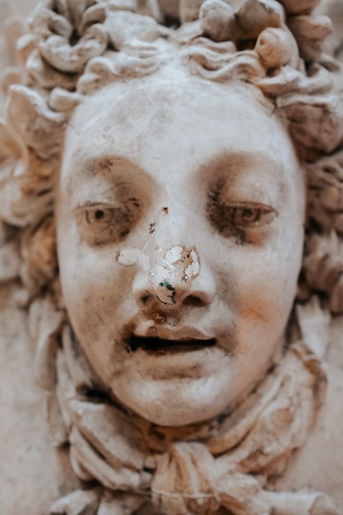 Free Intricate close-up of a weathered marble sculpture face, showing age and detail. Stock Photo