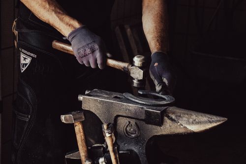 Free Close-up of a blacksmith forging a horseshoe indoors with tools. Stock Photo