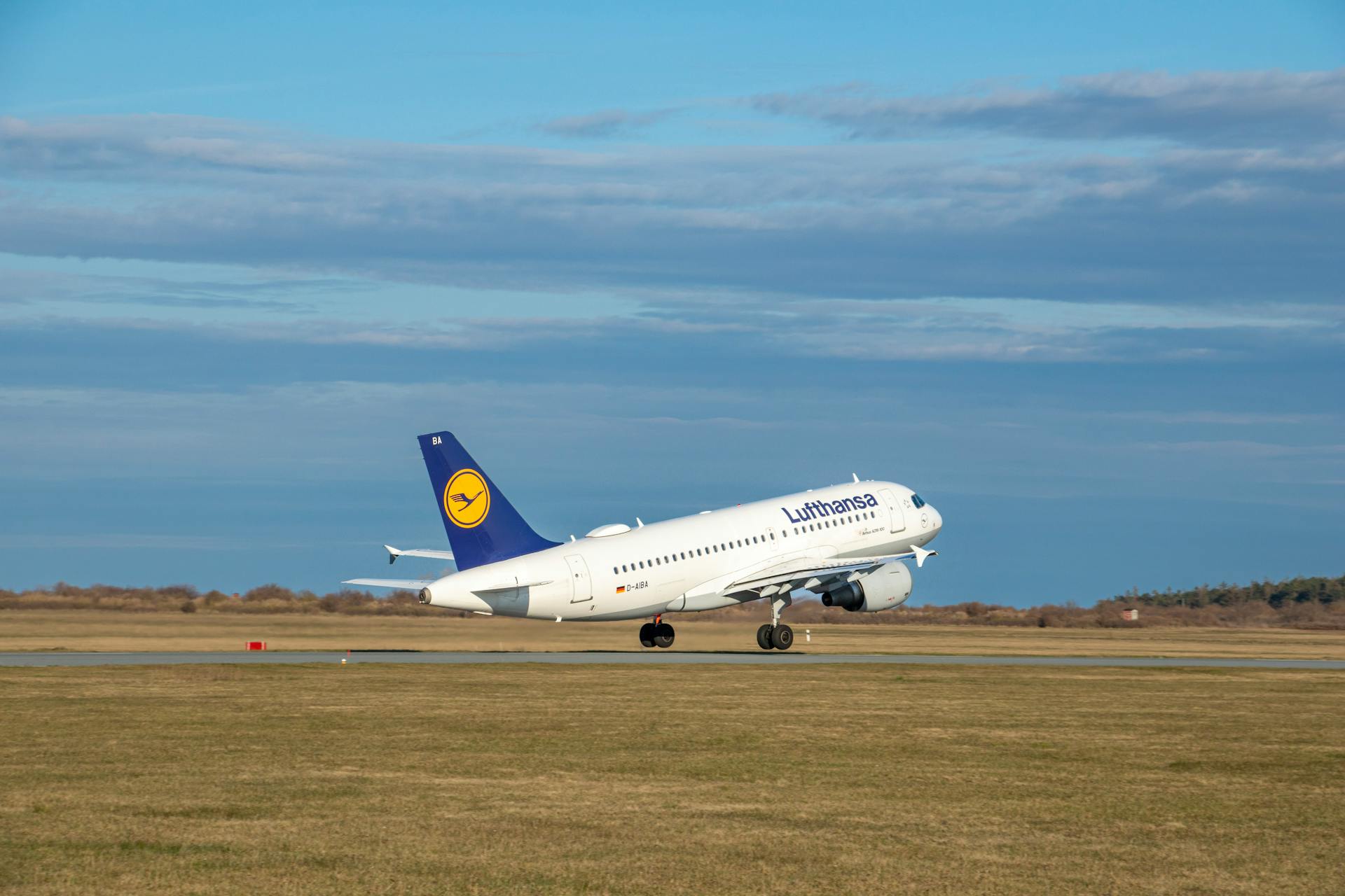 A Lufthansa airplane taking off from an airport runway, set against a clear blue sky.