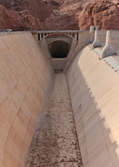 Free A monumental dam reveals its spillway and arch bridge, surrounded by rocky formations. Stock Photo