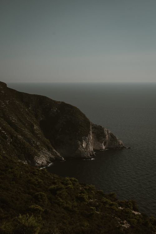 Free Dramatic rocky cliffs meet the serene sea under a clear sky on Zakynthos island. Stock Photo