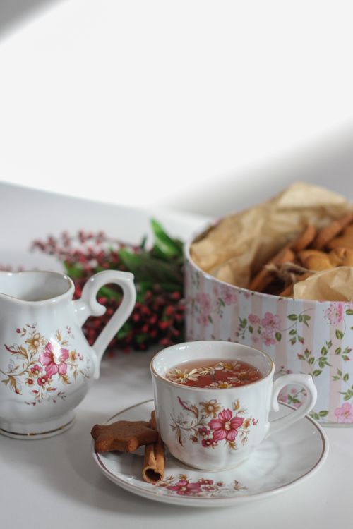 Free Elegant floral tea set with cinnamon sticks and a box of cookies for a cozy setting. Stock Photo