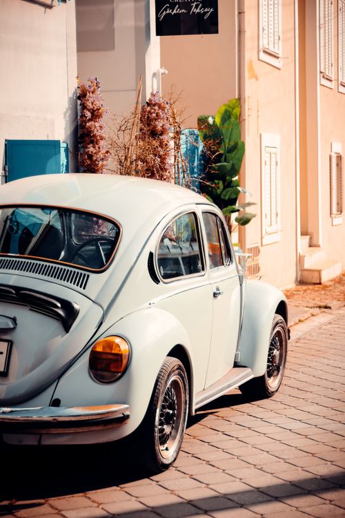 Free A classic vintage car parked on a quaint city street with warm sunlight. Stock Photo