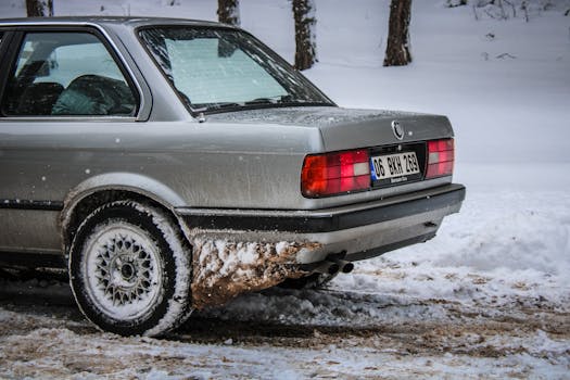 Vintage BMW E30 car with tail lights on in a snowy setting in Türkiye.