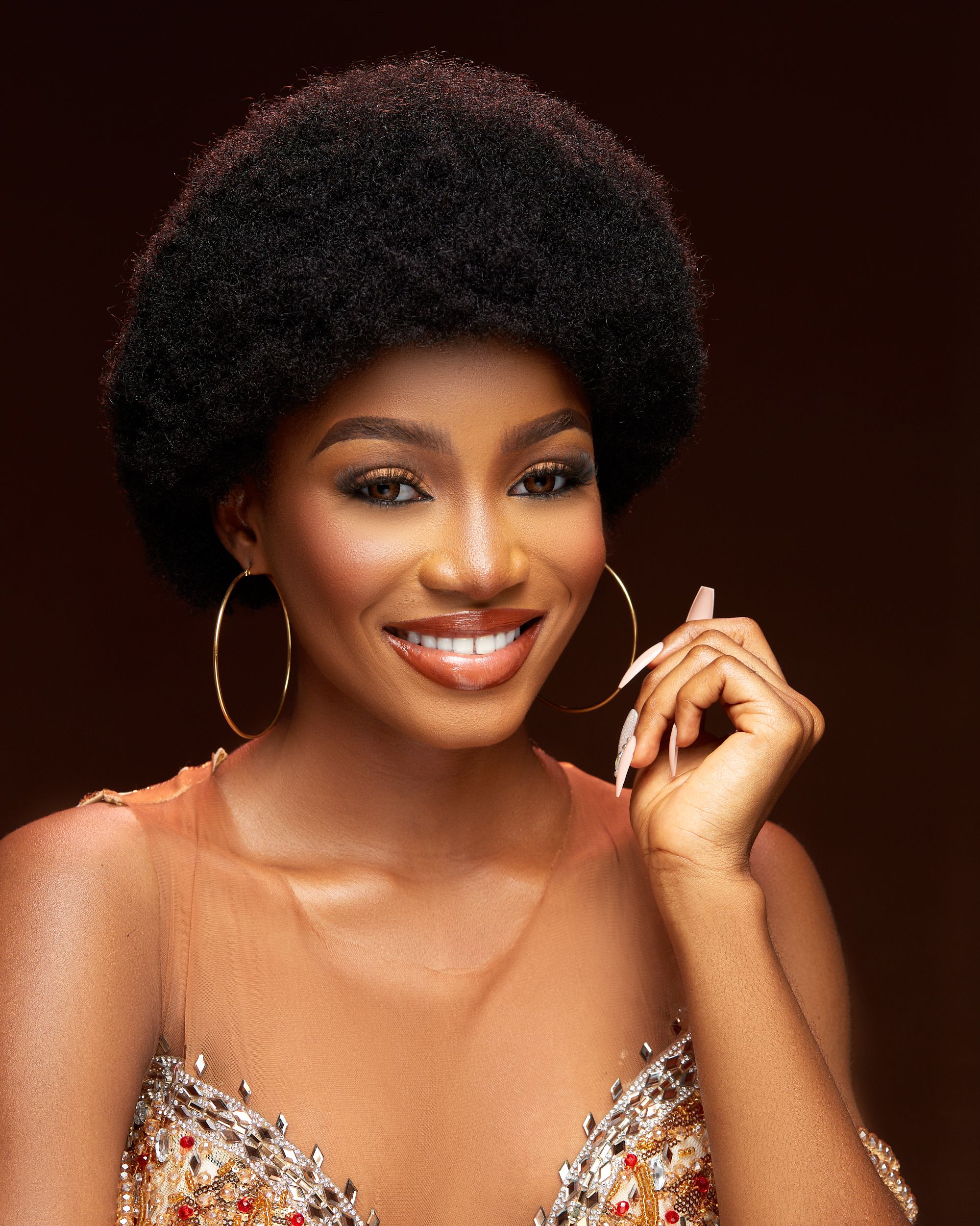 Close-up portrait of a smiling African woman with natural hair and elegant attire.