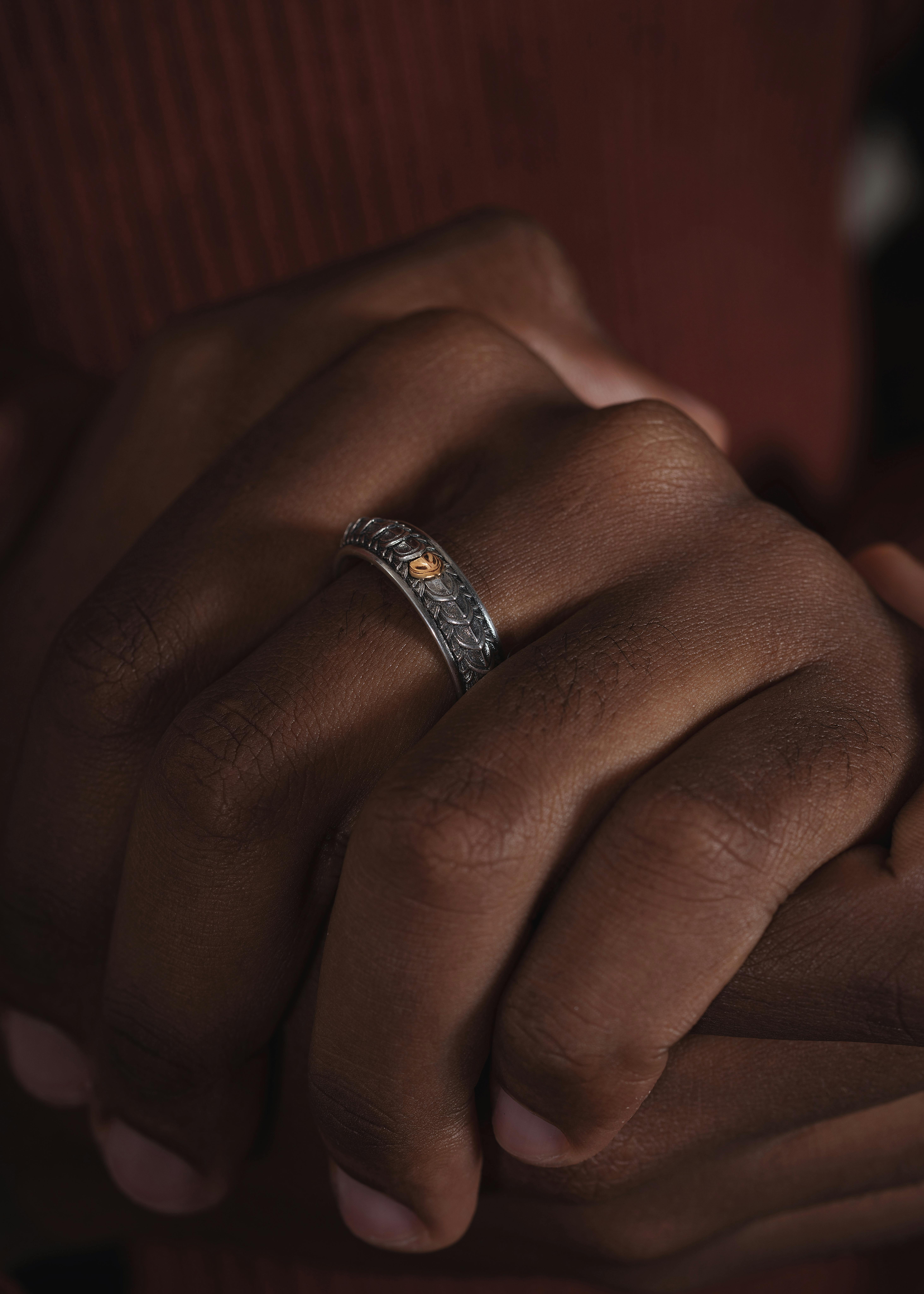 Intimate close-up of hands adorned with a detailed silver ring emphasizing elegance.