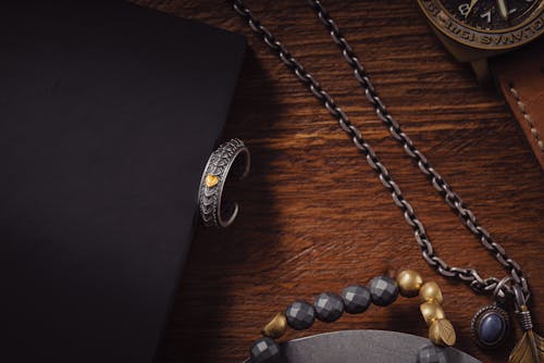 Ring, a Necklace and a Beaded Bracelet Lying on a Wooden Surface