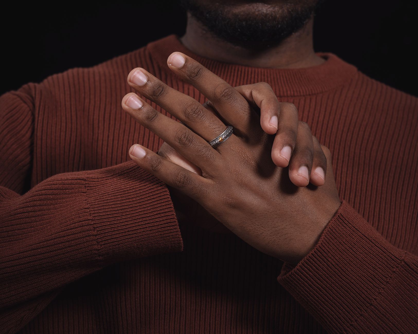 Close-up of hands with a silver ring, showcasing elegance and style against a dark background.