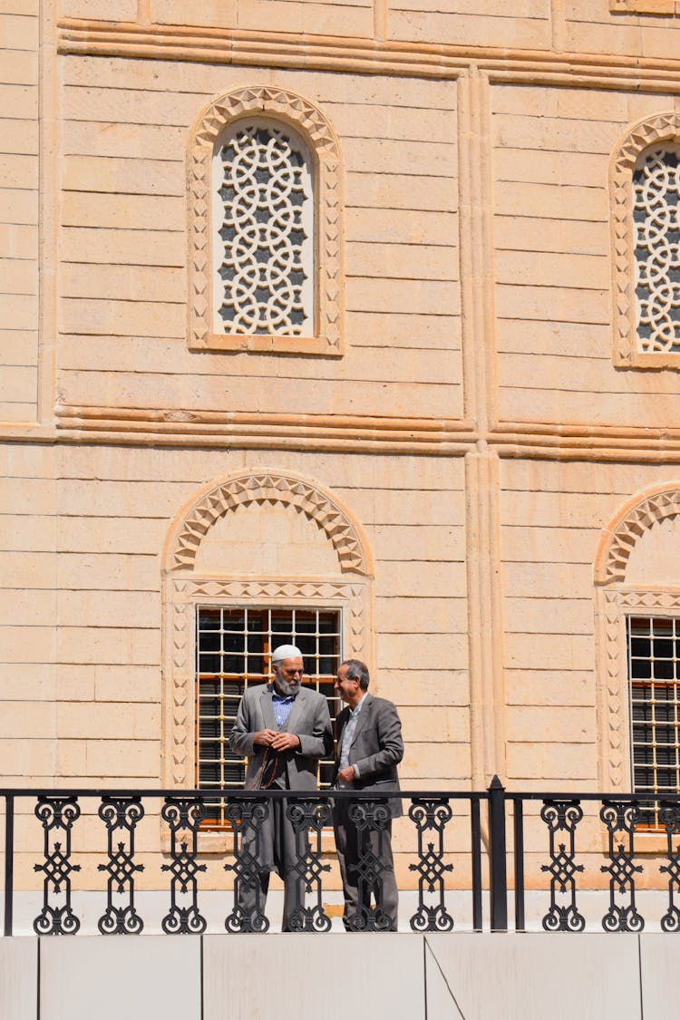 Two Men Talking On A Balcony 