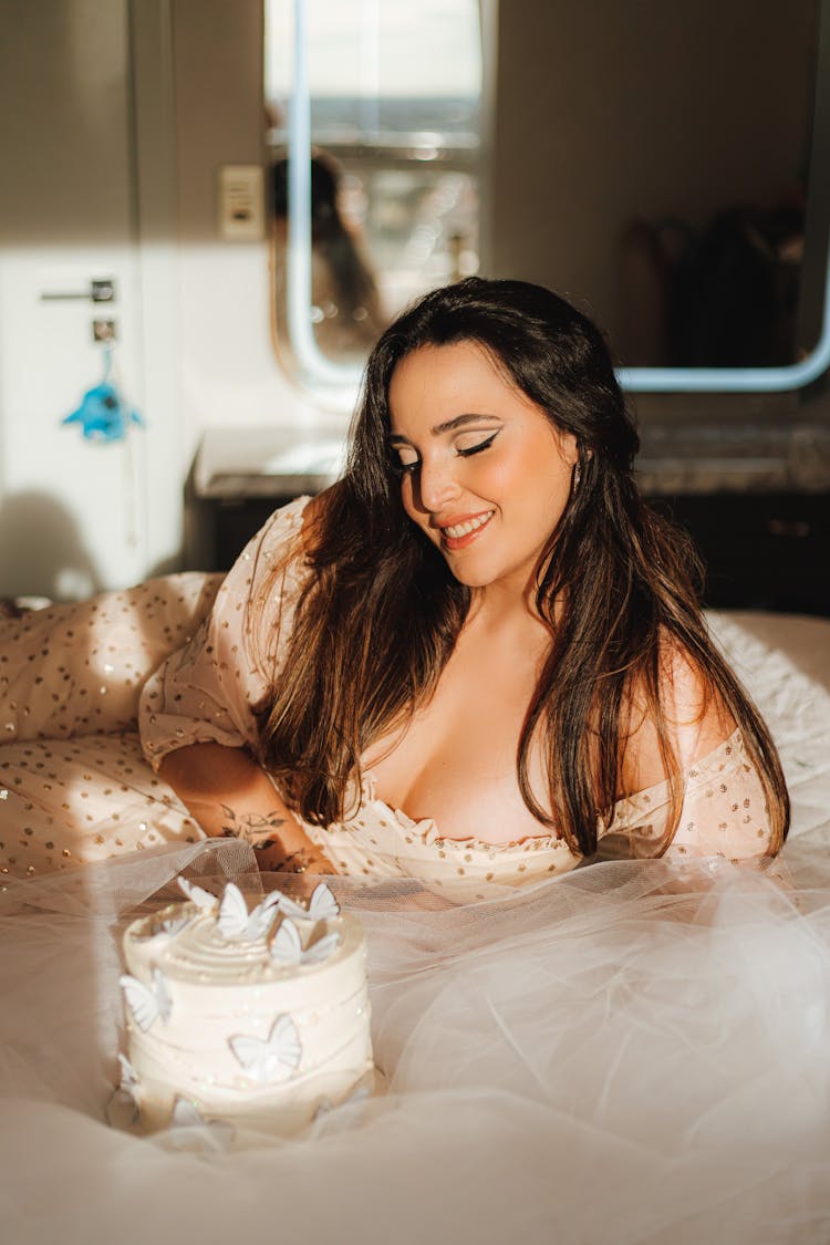 Smiling Woman With Birthday Cake Sitting On Bed