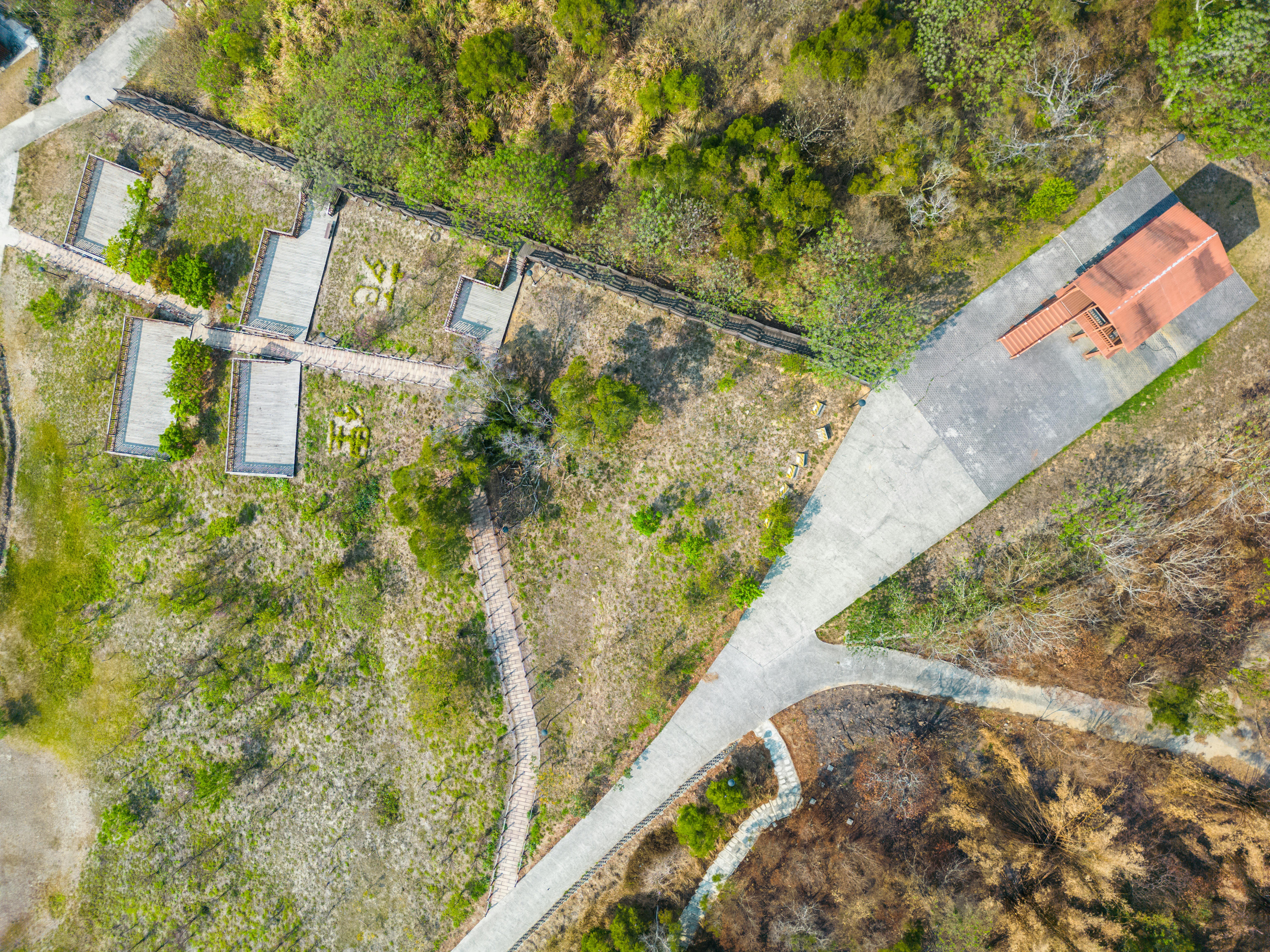 Free Aerial shot showing green park landscape with pathways and a red-roofed building. Stock Photo