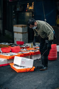 Fishmonger organizing fresh seafood in outdoor urban market scene. Vibrant and lively setting.