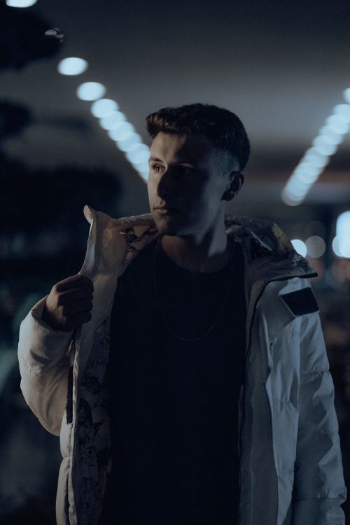 Free Portrait of a man in a white jacket posing under dramatic lighting indoors. Stock Photo