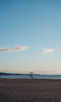 A peaceful beach with a lifeguard tower under a clear blue sky, perfect for serene moments by the sea.