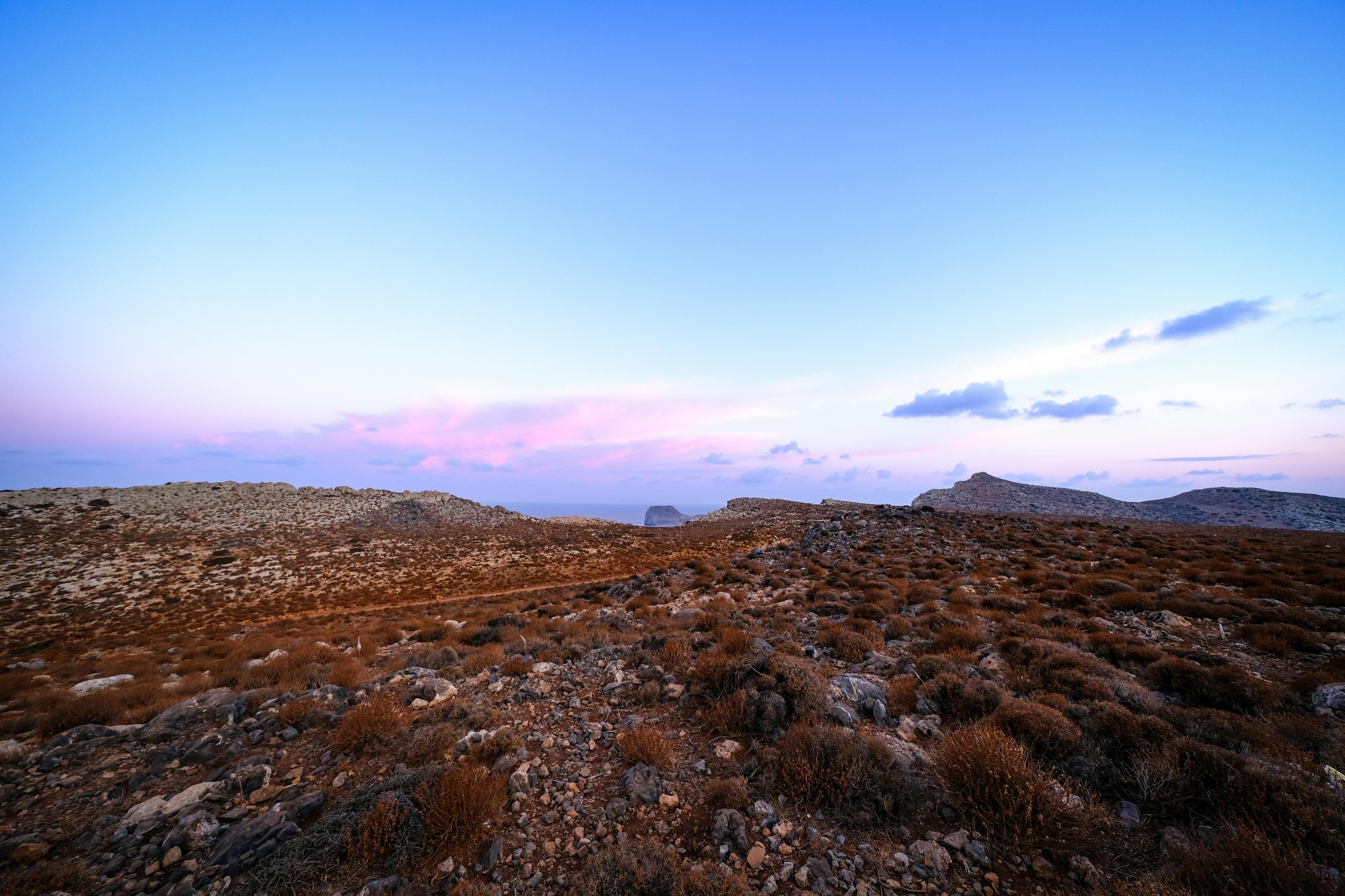 Beautiful arid landscape captured at dusk with a tranquil pink sky and rugged terrain.