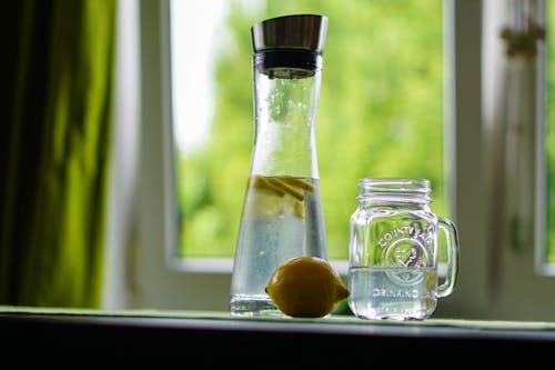 Fotografia A Fuoco Poco Profondo Di Limone Giallo Vicino A Un Barattolo Di Vetro E Un Decanter Di Vetro