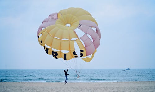 Boy Jumping under Parachute on Beach