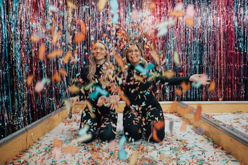 Free Two Women Kneeling While Throwing Confetti Stock Photo