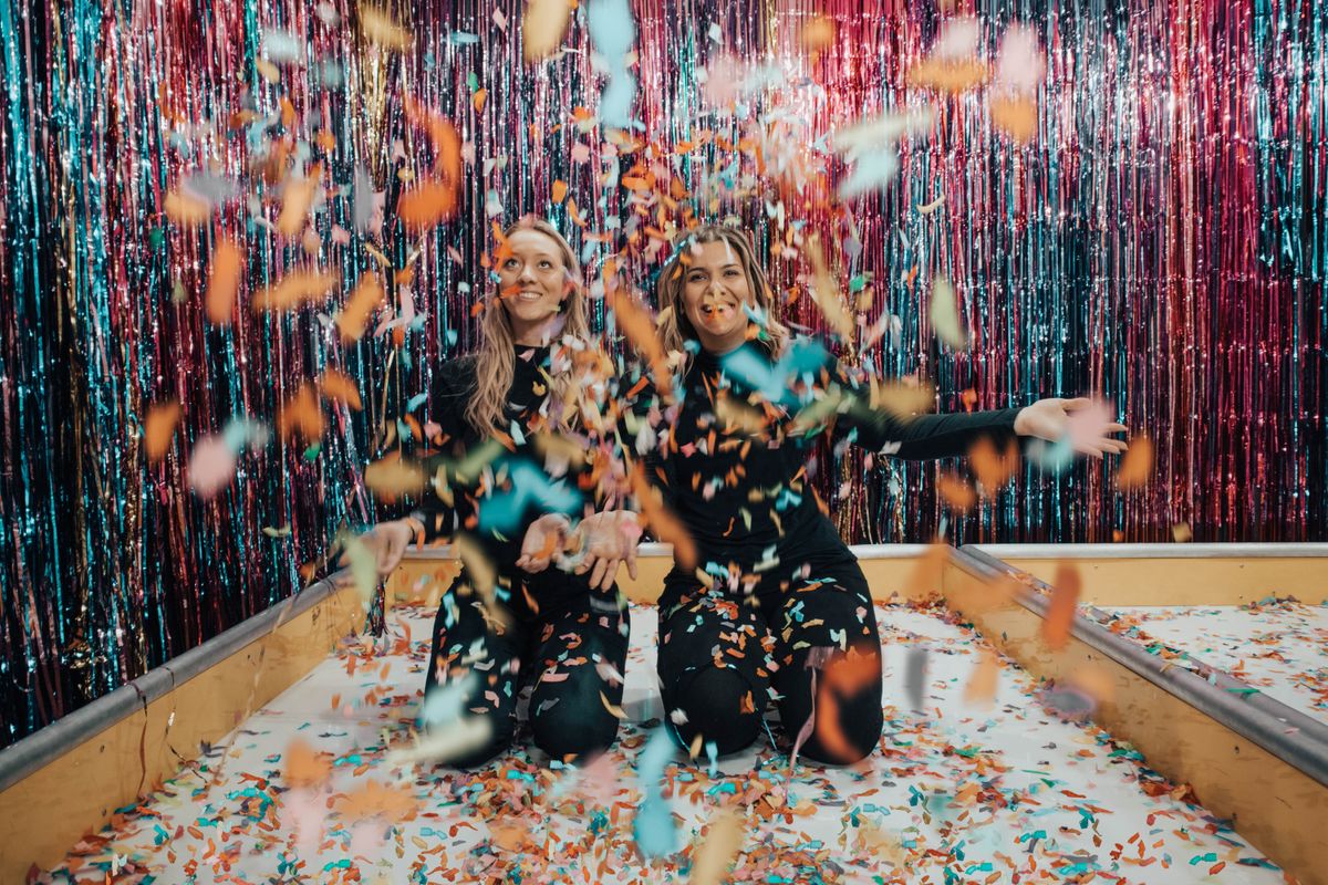Baby shower photo booth ideas with two women throwing confetti at a celebration