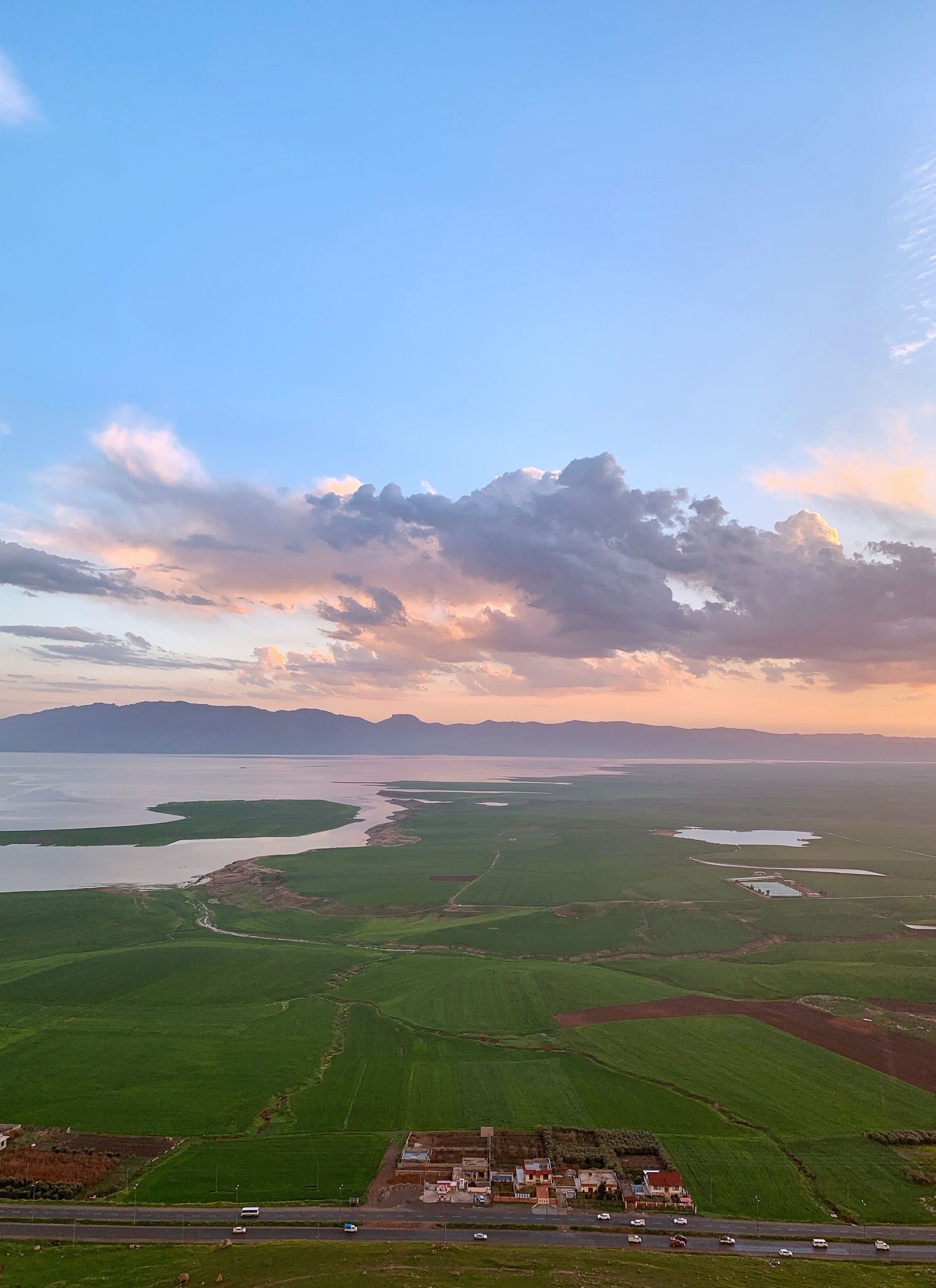 Breathtaking aerial landscape of Lake Dukan in Ranya, Iraq at sunset, surrounded by vibrant fields.