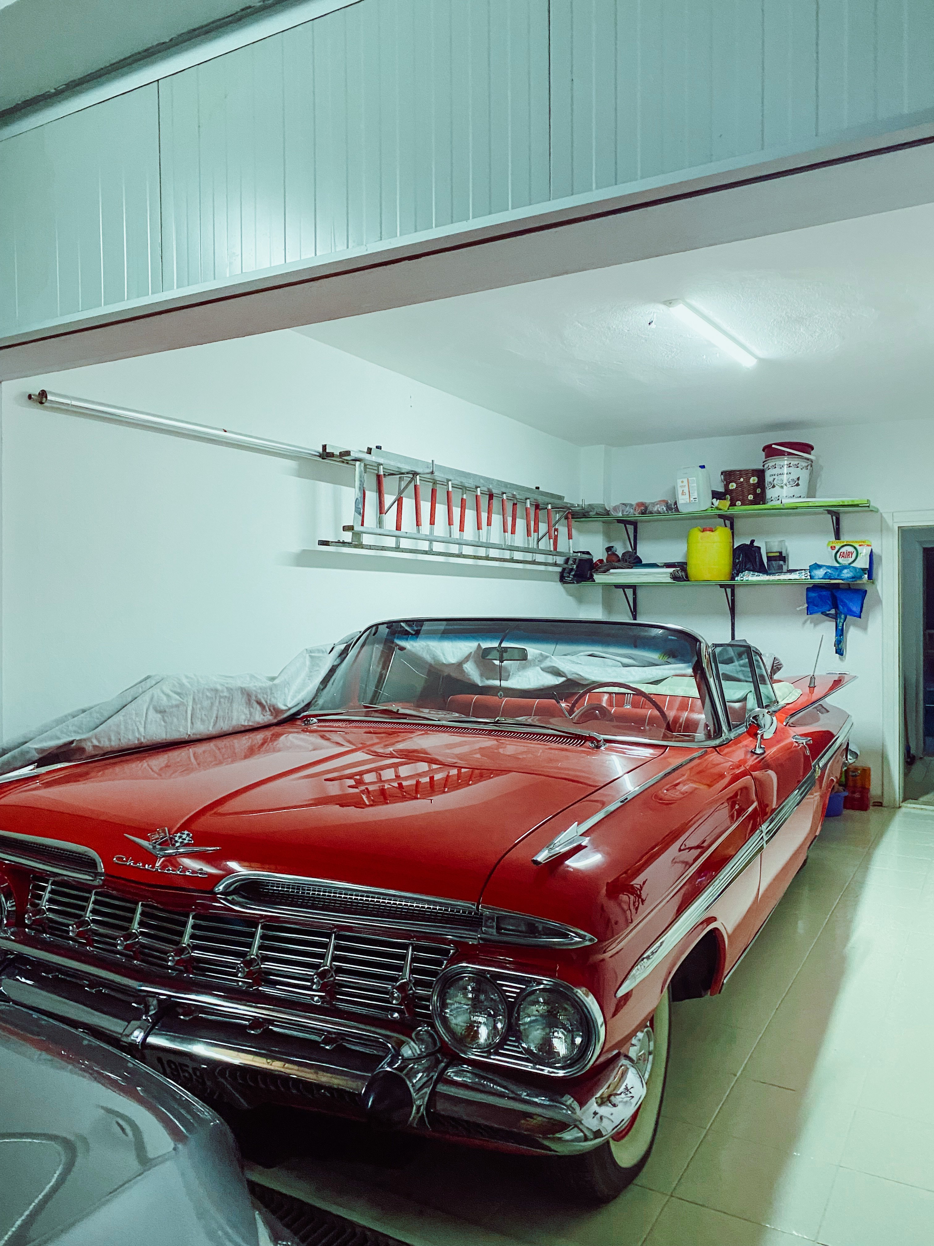 Chevrolet Impala vermelho clássico estacionado numa garagem bem organizada.