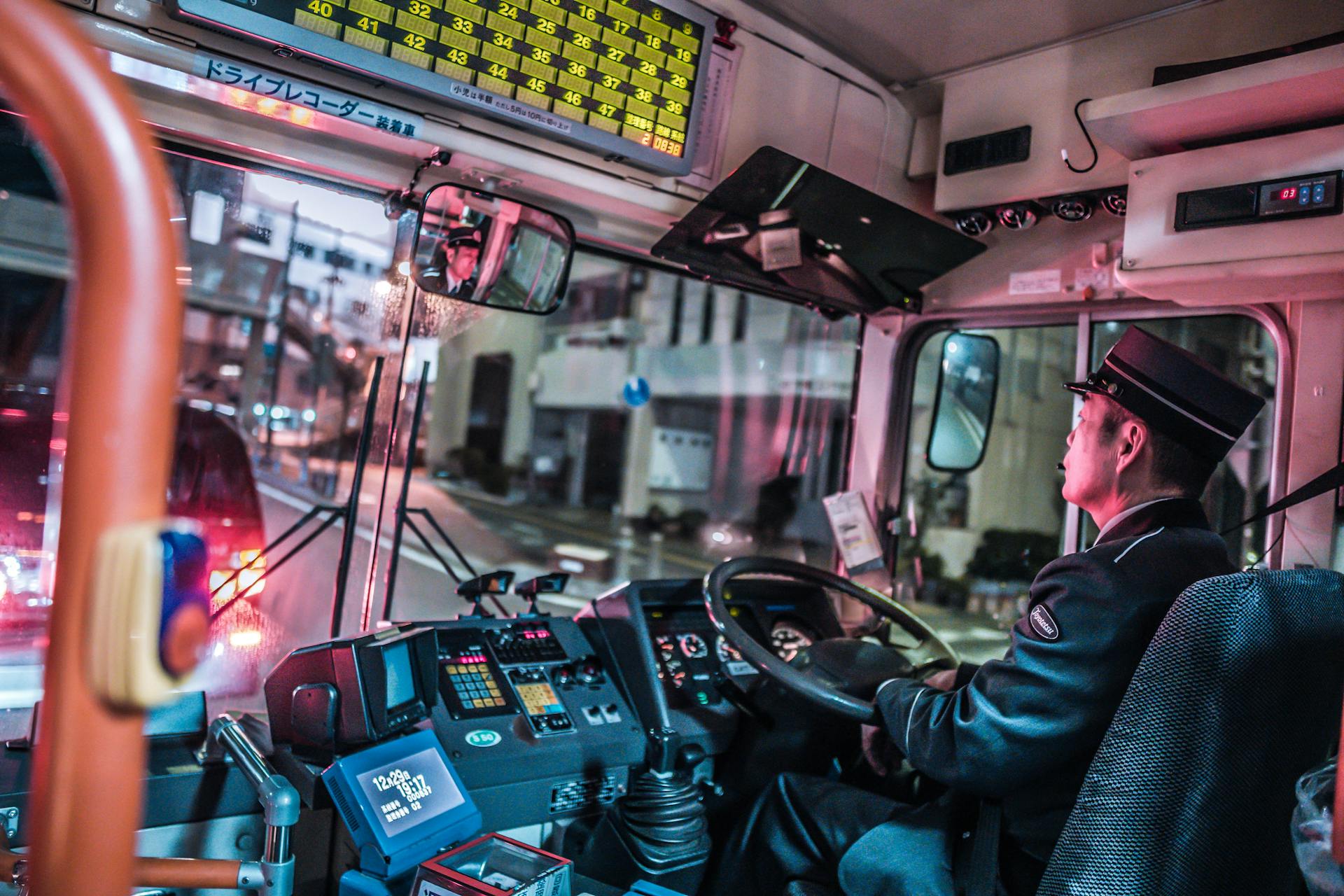 A city bus driver navigates the streets at night, showcasing public transportation in an urban setting.