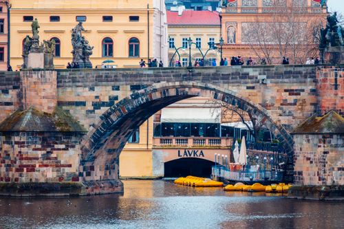 Free View of the Charles Bridge in Prague with historic sculptures and riverfront architecture. Stock Photo