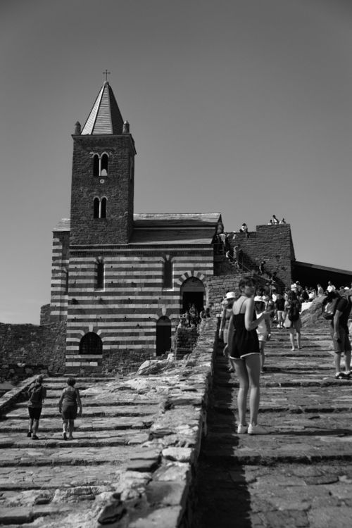 Free San Lorenzo Church with visitors on stairs in La Spezia, Italy; a sunlit architectural landmark. Stock Photo