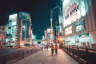 日本城市的夜晚，建筑物灯火通明，街上行人往来