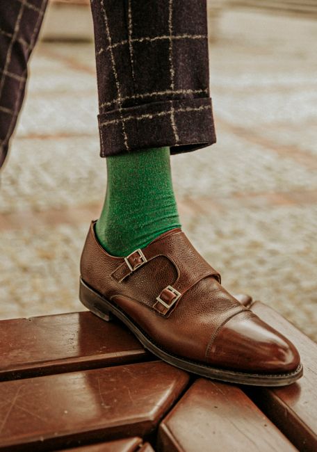 Close-up of a stylish brown monk shoe with green sock, showcasing elegant menswear fashion in a vertical shot.