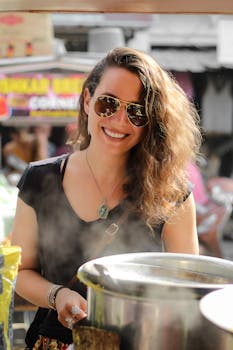 Cheerful woman with sunglasses cooking at a lively street food market.