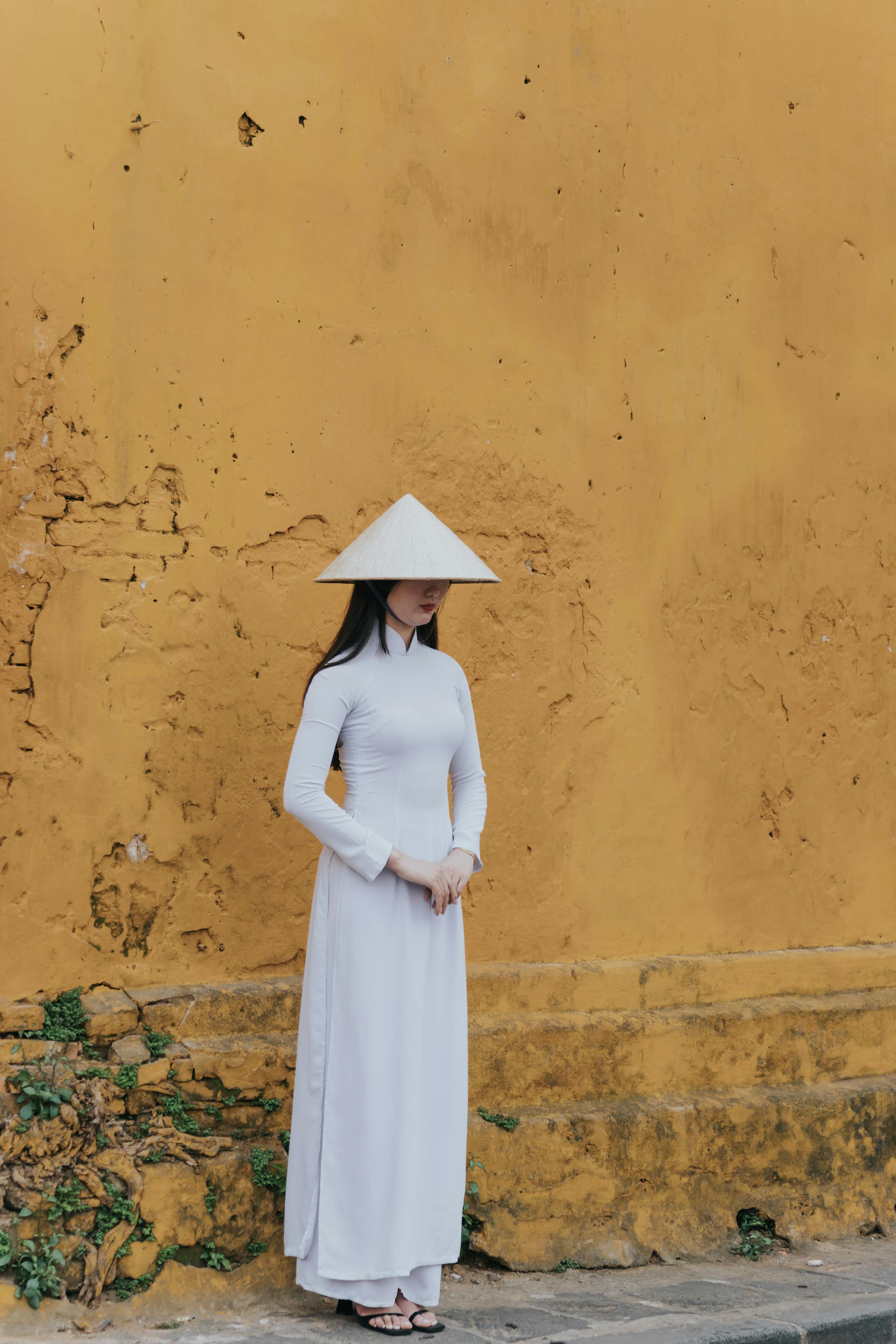 Beautiful woman in traditional attire standing against a vivid yellow wall.
