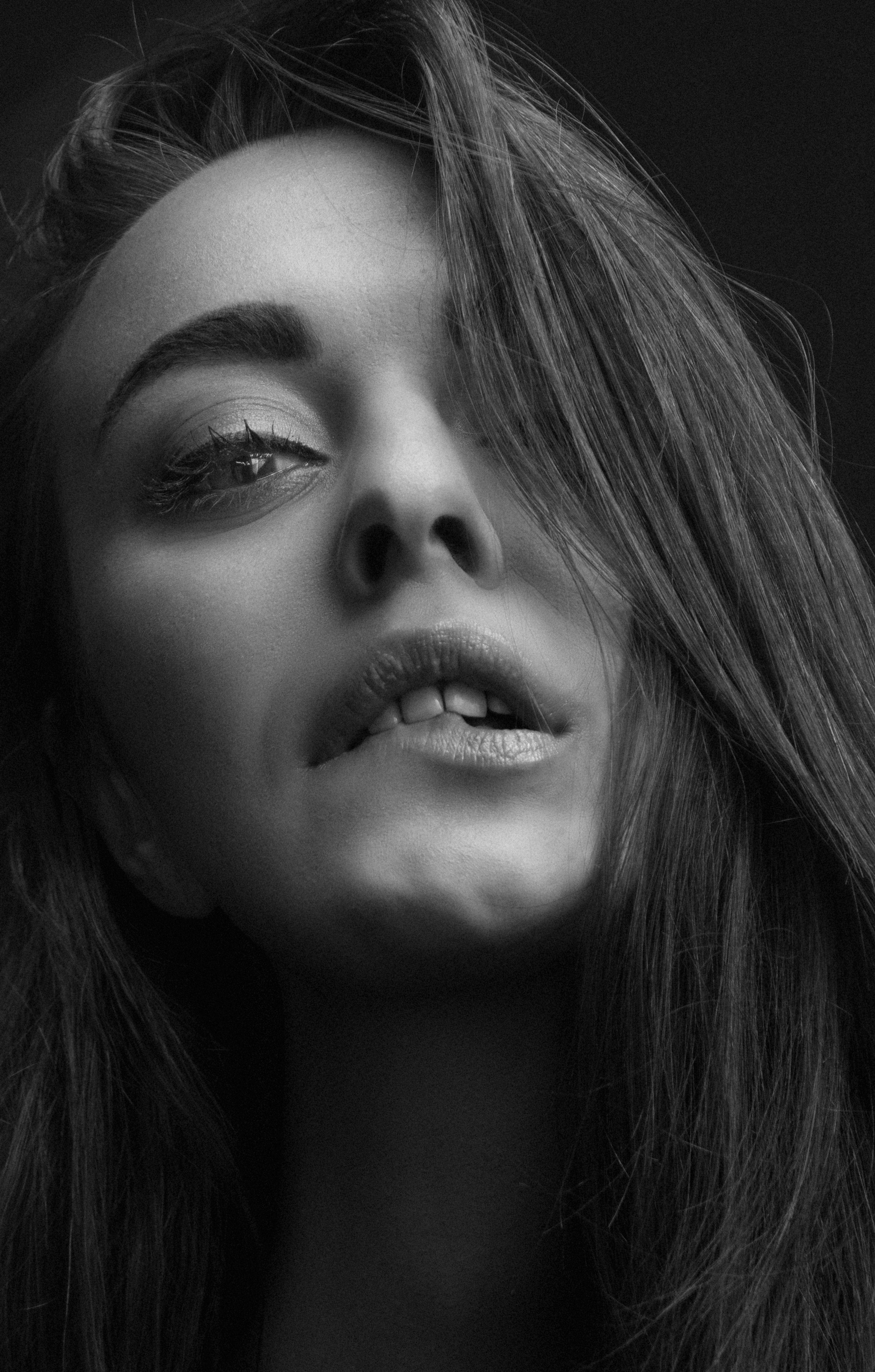 Artistic black and white headshot of woman with long hair and captivating expression.