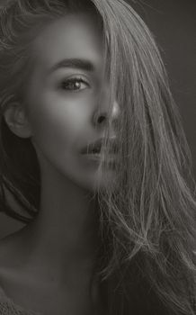 Striking black and white portrait of a woman with long hair, evokes mystery and elegance.