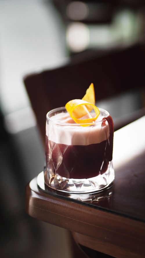 Free A sophisticated cocktail featuring a foam layer and orange twist garnish, perfect for upscale settings. Stock Photo