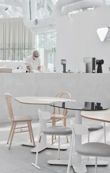 Elegant minimalist restaurant interior featuring a chef at work, emphasizing clean lines and contemporary design.